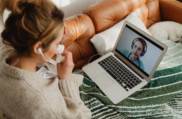 A person sick with the flu consulting with a medical professional via telehealth