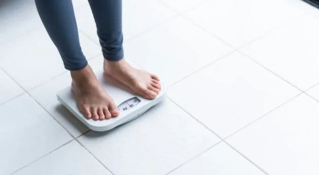 Person on weighing scale for the blog post on skin volume loss after weight loss