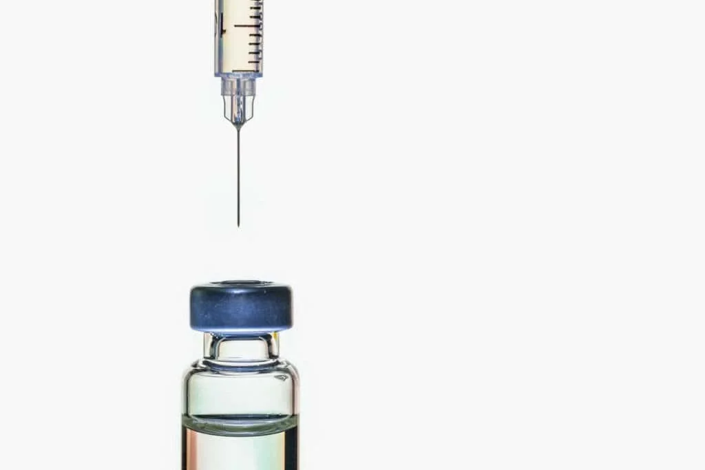 Photo of a syringe about to pierce a vial of the peptide Sermorelin