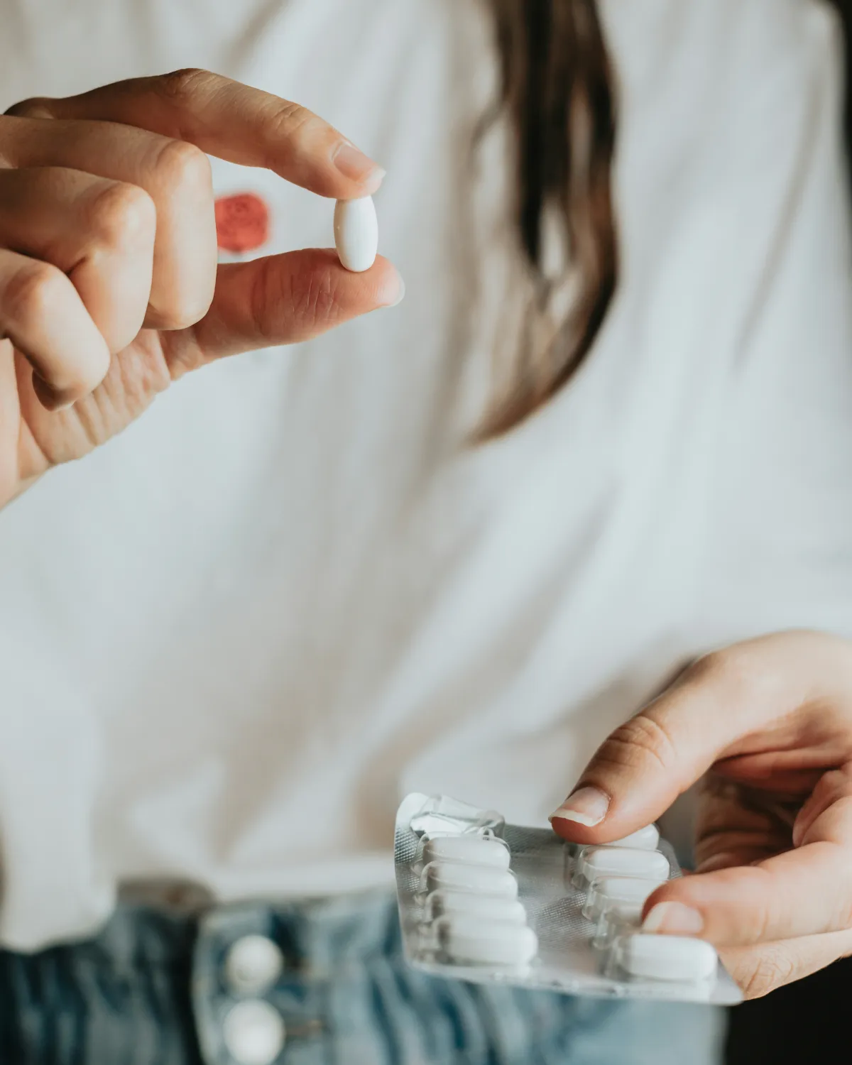 Patient holding a white tablet and a blister pack of medication