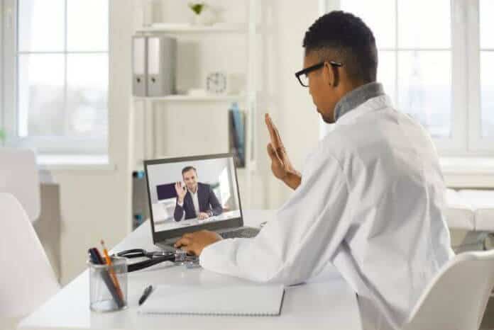 Medical professional conducting a remote consultation, using a laptop to assess and provide care for a patient.